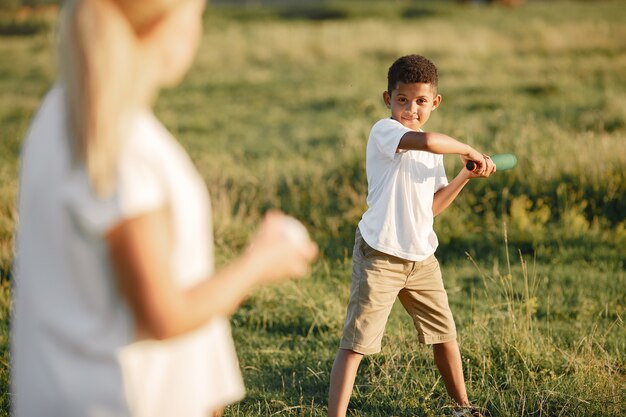 Europäische Mutter und afrikanischer Sohn. Familie in einem Sommerpark. Die Leute spielen mit Biss und Ball.