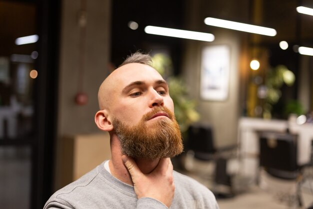 Europäischer brutaler Mann mit einem Bartschnitt in einem Friseurladen