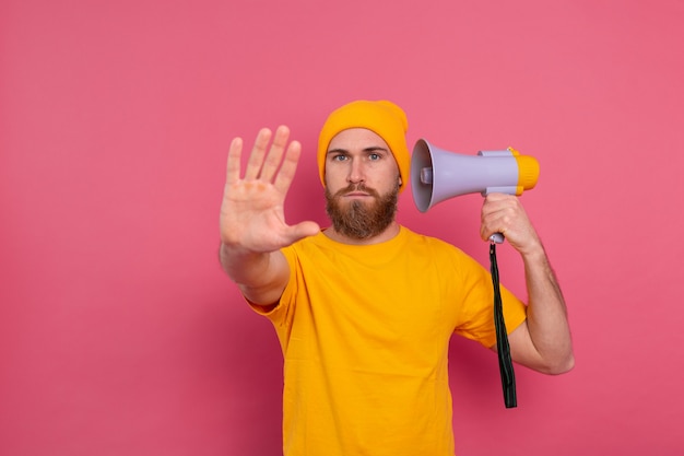 Kostenloses Foto europäischer mann halten megaphon zeigen stoppschild auf rosa hintergrund