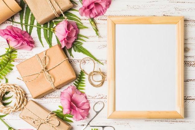 Kostenloses Foto eustomablume und verpackte geschenke mit leerem rahmen auf tabelle