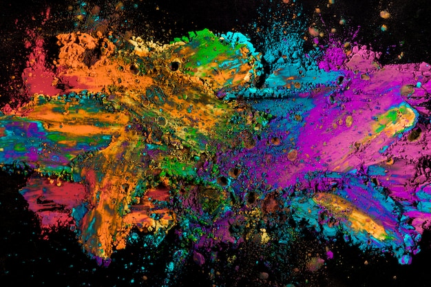 Explosion des farbigen Pulvers auf schwarzer Oberfläche