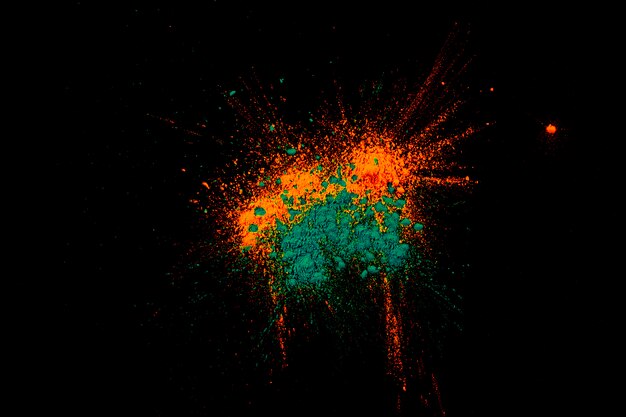 Explosion von farbigem Pulver auf dunkler schwarzer Oberfläche