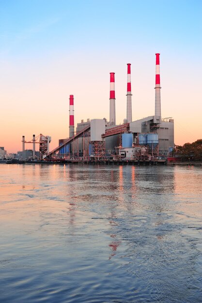 Fabrik über dem Fluss in der Abenddämmerung