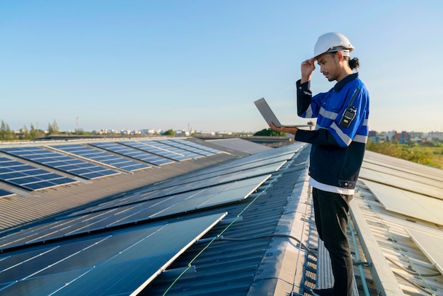 Fachtechniker Fachingenieur mit Laptop- und Tablet-Wartungsprüfung Installation von Solardachpaneelen auf dem Dach der Fabrik unter Sonnenlicht Ingenieure, die ein Tablet halten, überprüfen das Solardach