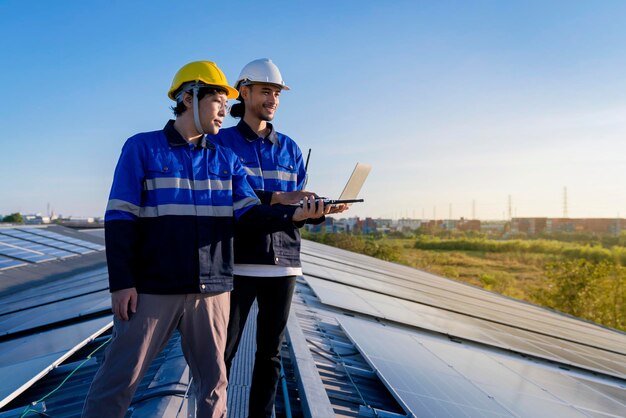 Fachtechniker professioneller Ingenieur mit Laptop- und Tablet-Wartungsprüfung Installation von Solardachpaneelen auf dem Dach der Fabrik unter Sonnenlicht Umfrage des Ingenieurteams überprüft Solarpaneeldach