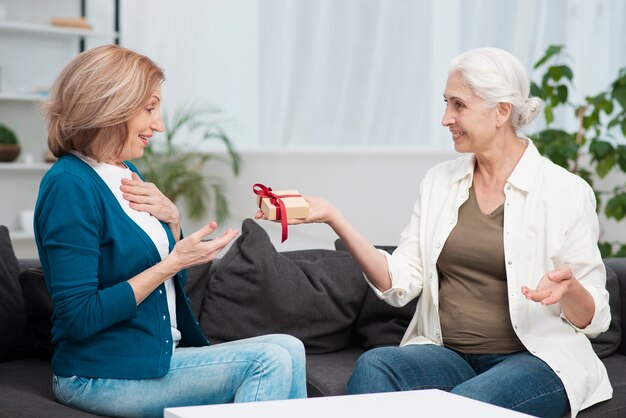 Fällige Frau, die ihren Freund mit einem Geschenk überrascht