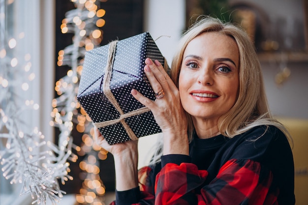 Fällige Frau mit Weihnachtsgeschenk durch bthe Fenster