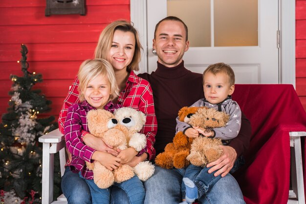 Familie auf Bank neben Weihnachtsbaum