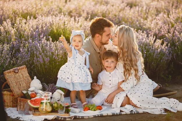 Familie auf Lavendelfeld. Leute auf einem Picknick. Mutter mit Kindern isst Früchte.