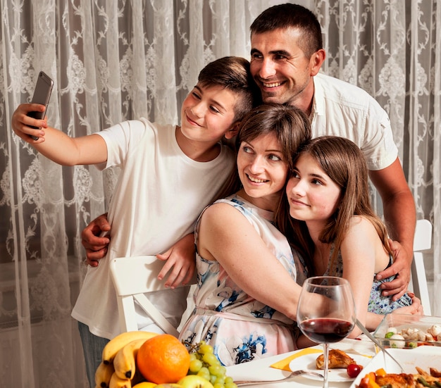 Familie, die beim Abendessen Selfie zusammen nimmt