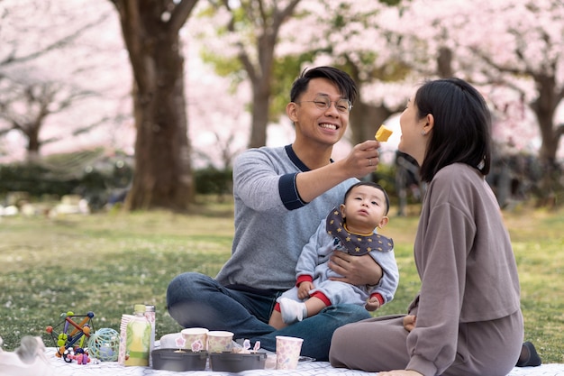 Familie, die ein picknick neben einem kirschbaum hat