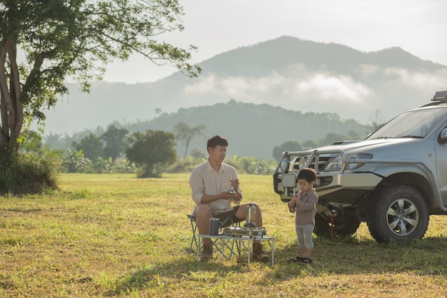 Familie, die ein Picknick neben ihrem Wohnmobil hat. Vater und Sohn spielen in den Bergen zur Sonnenuntergangszeit.