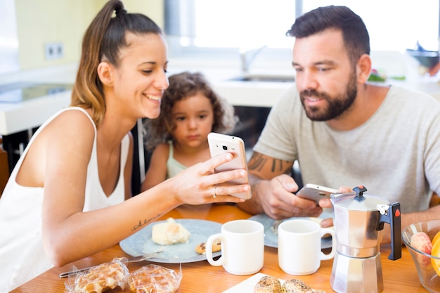 Familie, die Handyschirm während des Frühstücks betrachtet