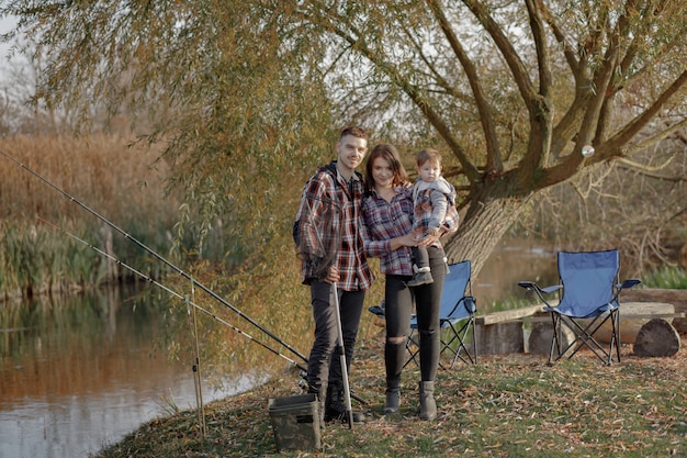 Familie, die in der Nähe des Flusses an einem Fischermorgen sitzt