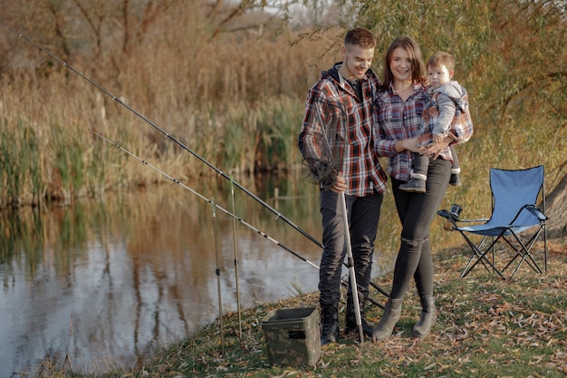 Familie, die in der Nähe des Flusses an einem Fischermorgen sitzt