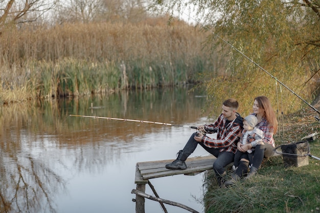 Familie, die in der Nähe des Flusses an einem Fischermorgen sitzt