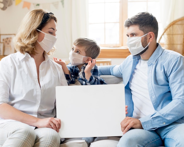 Familie, die medizinische Masken drinnen trägt, kopiert Raum