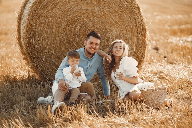 Familie, die mit dem kleinen Sohn im Weizenfeld auf Sonnenuntergang spielt. Leute auf einem Picknick. Familie verbringt Zeit miteinander in der Natur.