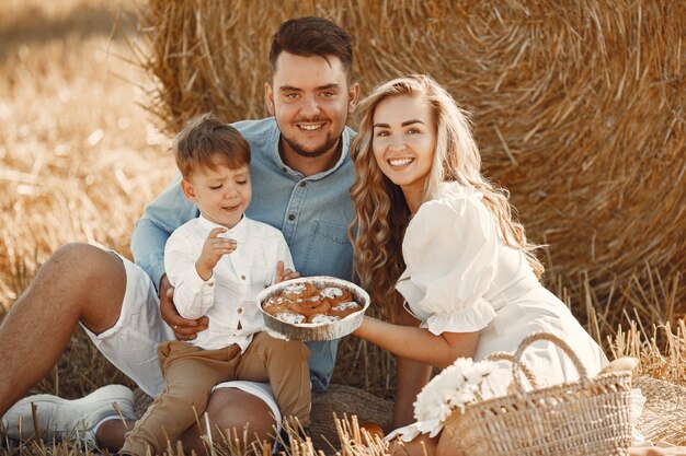 Familie, die mit dem kleinen Sohn im Weizenfeld auf Sonnenuntergang spielt. Leute auf einem Picknick. Familie verbringt Zeit miteinander in der Natur.