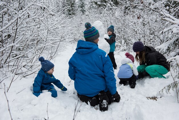 Familie, die Schneemann am verschneiten Tag macht