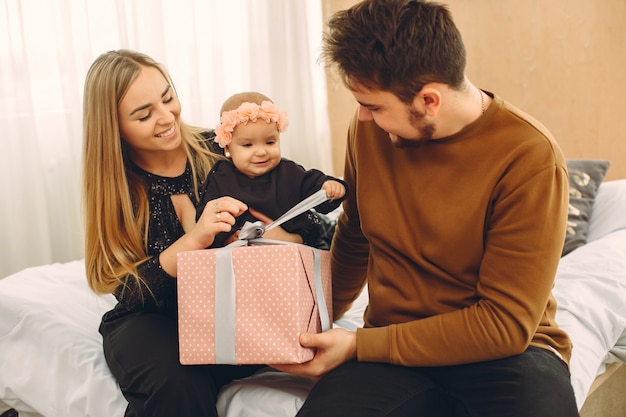 Familie, die zu Hause auf einem Bett mit Geschenken sitzt