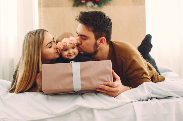 Familie, die zu Hause auf einem Bett mit Geschenken sitzt