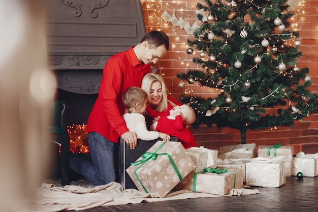 Familie, die zu Hause nahe Weihnachtsbaum sitzt