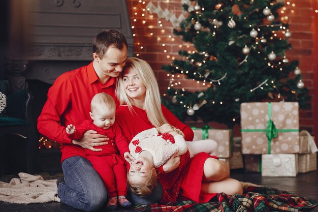 Familie, die zu Hause nahe Weihnachtsbaum sitzt