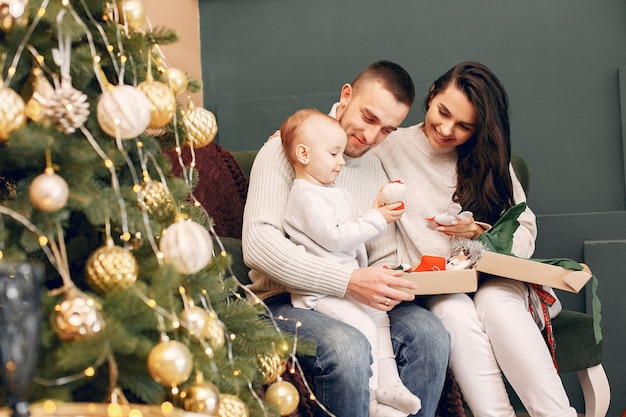 Familie, die zu Hause nahe Weihnachtsbaum sitzt