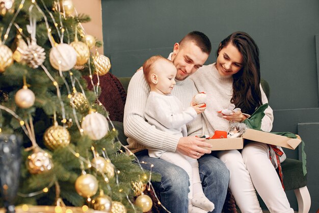 Familie, die zu Hause nahe Weihnachtsbaum sitzt