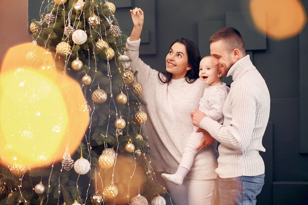 Familie, die zu Hause nahe Weihnachtsbaum sitzt