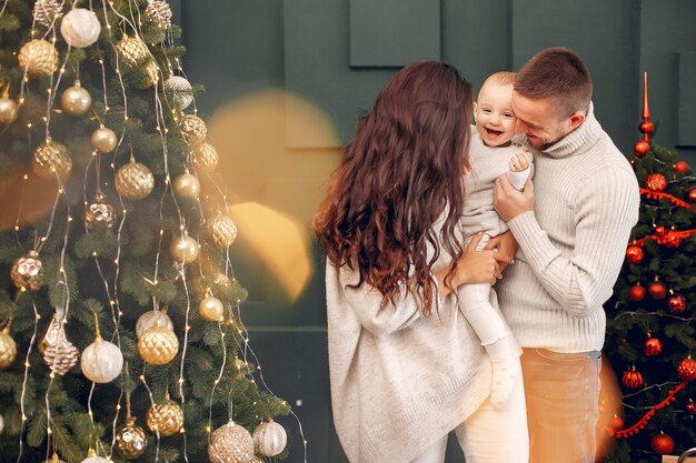 Familie, die zu Hause nahe Weihnachtsbaum sitzt