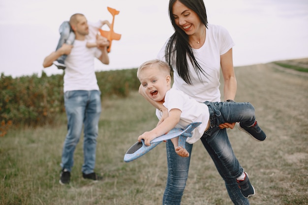 Familie geht in ein Feld und spielt mit Spielzeugflugzeug