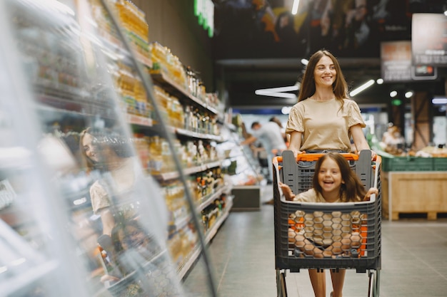 Familie im Supermarkt. Frau in einem braunen T-Shirt. Menschen wählen Produkte. Mutter mit Tochter.