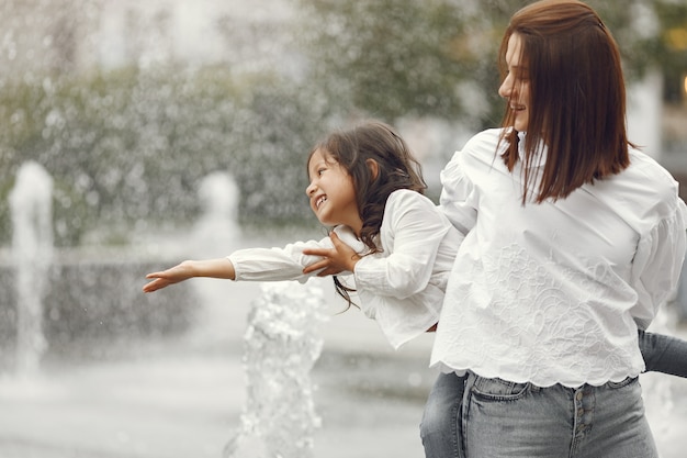 Familie in der Nähe des Stadtbrunnens. Mutter mit Lachen spielt mit Wasser.