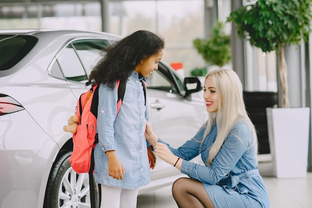 Familie in einem Autosalon. Frau, die das Auto kauft. Kleines afrikanisches Mädchen mit mther.