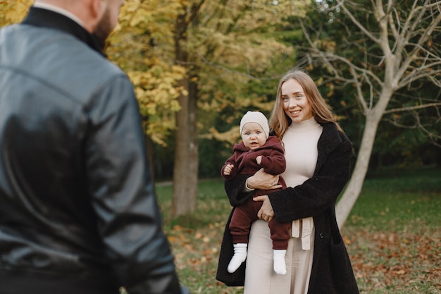 Familie in einem Herbstpark. Mann in einer schwarzen Jacke. Nettes kleines Mädchen mit den Eltern.