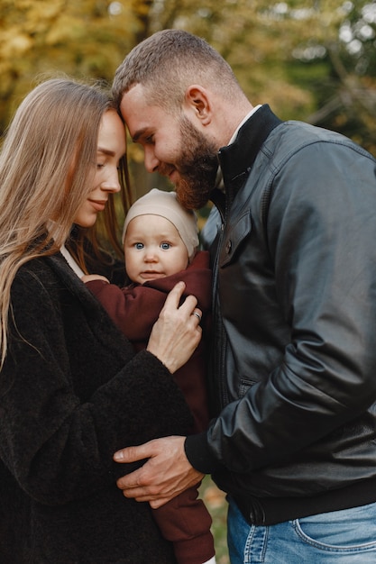 Familie in einem Herbstpark. Mann in einer schwarzen Jacke. Nettes kleines Mädchen mit den Eltern.