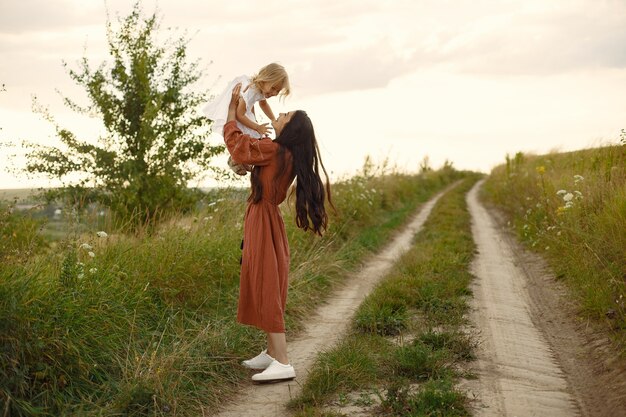 Familie in einem Sommerfeld. Mutter in einem braunen Kleid. Süßes kleines Mädchen.