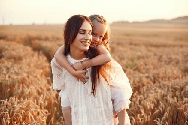 Familie in einem Sommerfeld. Sinnliches Foto. Süßes kleines Mädchen. Frau in einem weißen Kleid.