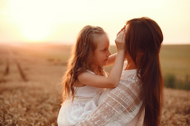 Familie in einem Sommerfeld. Sinnliches Foto. Süßes kleines Mädchen. Frau in einem weißen Kleid.