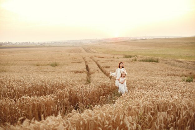 Familie in einem Sommerfeld. Sinnliches Foto. Süßes kleines Mädchen. Frau in einem weißen Kleid.