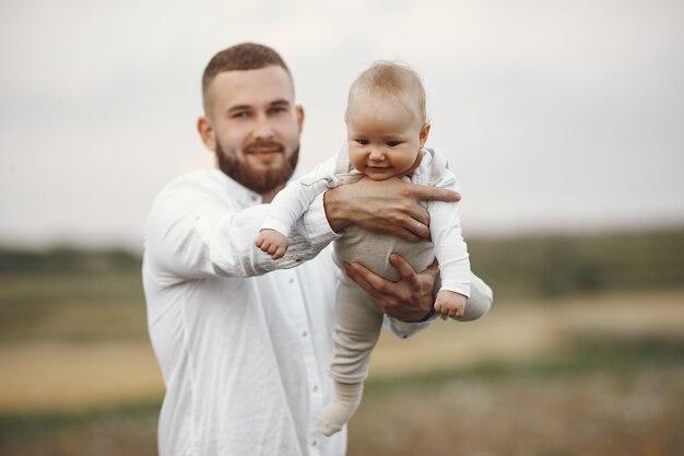 Familie in einem Sommerfeld. Vater in einem weißen Hemd. Süße neugeborene Tochter.