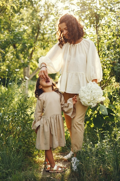 Familie in einem Sommergarten. Sinnliches Foto. Süßes kleines Mädchen. Frau mit Blumenstrauß.