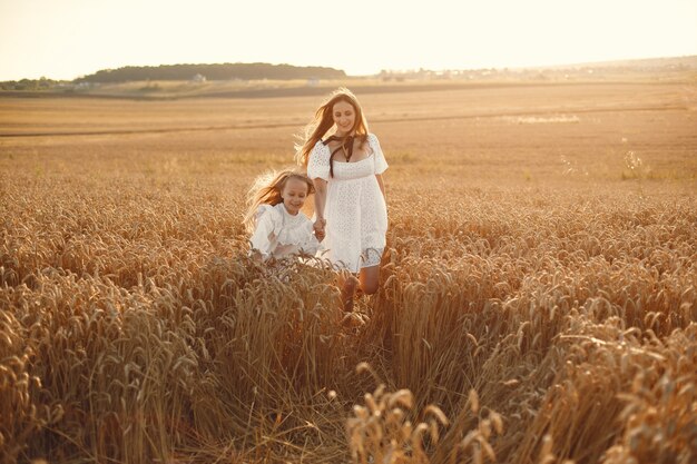 Familie in einem Weizenfeld. Frau in einem weißen Kleid. Mädchen mit Strohhut.