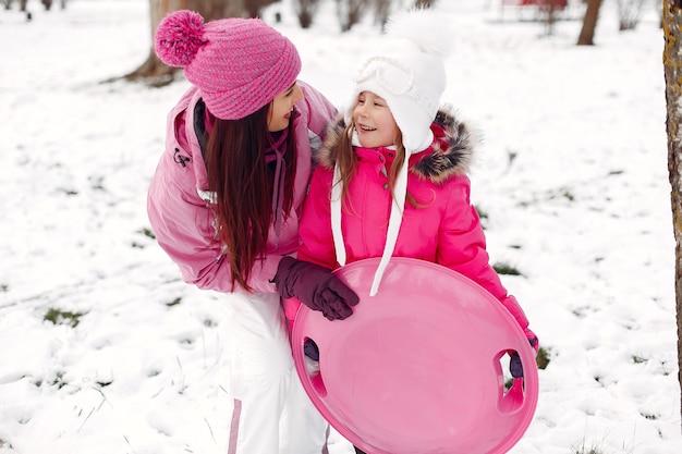 Familie in gestrickten Wintermützen auf Familienweihnachtsferien. Frau und kleines Mädchen in einem Park. Leute spielen.