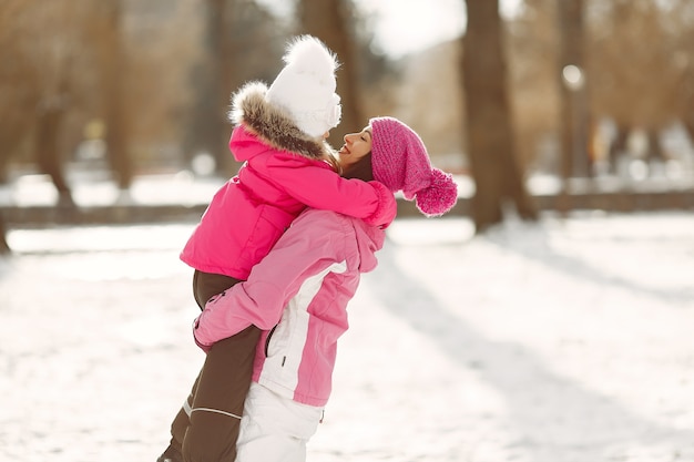Familie in gestrickten Wintermützen auf Familienweihnachtsferien. Frau und kleines Mädchen in einem Park. Leute spielen.