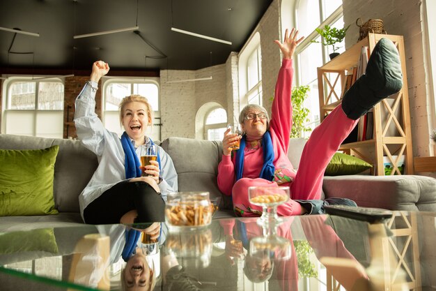 Familie jubelt und sieht zu Hause im Wohnzimmer fern