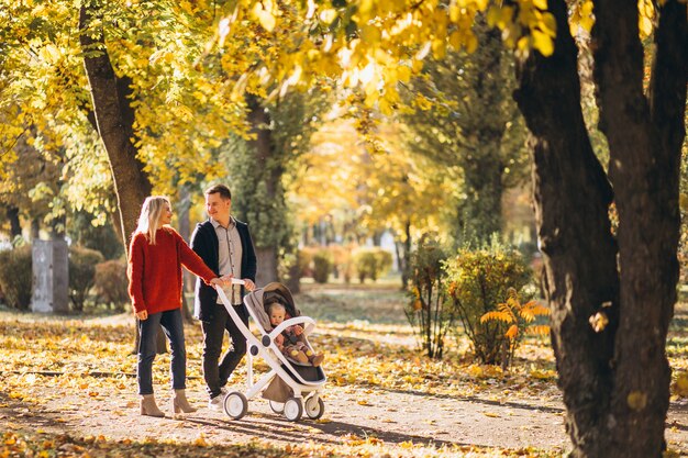 Familie mit Baby daugher in einem Kinderwagen gehend ein Herbstpark