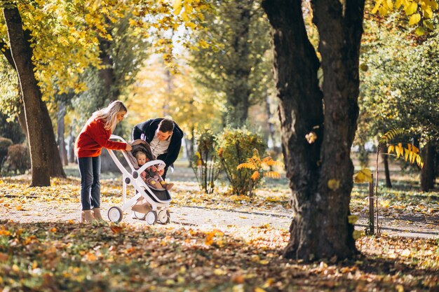 Familie mit Baby daugher in einem Kinderwagen gehend ein Herbstpark